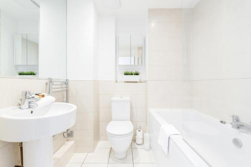 a white bathroom with a sink and a toilet and a tub at Roomspace Serviced Apartments - Abbot's Yard in Guildford