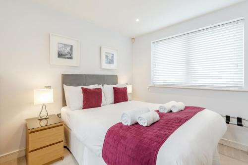 um quarto com uma grande cama branca com toalhas em Roomspace Serviced Apartments - Abbot's Yard em Guildford