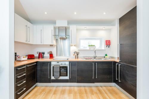 cocina con armarios negros y suelo de madera en Roomspace Serviced Apartments - Abbot's Yard, en Guildford
