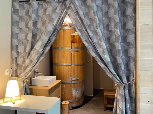 a room with a curtain and a sink and a table at Le Milan pour 10 et son bain nordique privatif in Camous