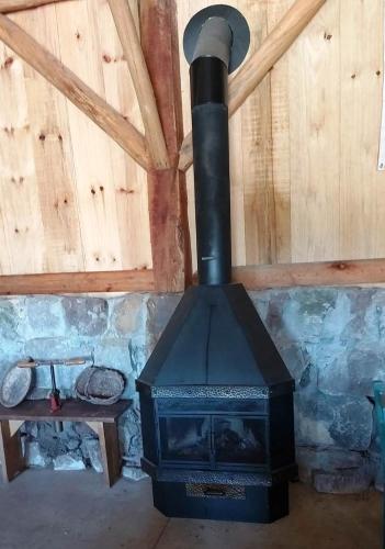 a black stove in a room with a stone wall at Casarão Biazolli in Farroupilha