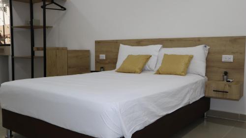 D'Rio Aparta estudios في ريوهاتشا: سرير كبير بملاءات بيضاء ومخدات صفراء