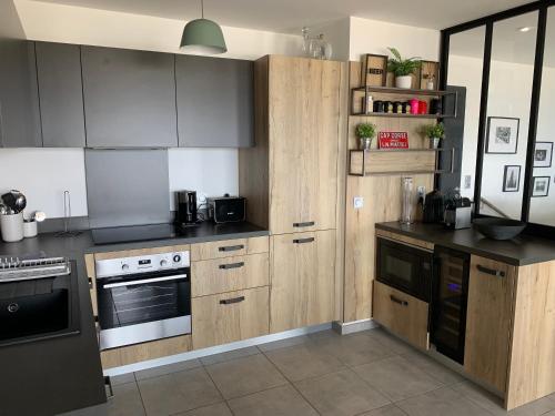 - une cuisine avec des placards en bois et une cuisinière dans l'établissement Duplex Horizon vue mer, à Pietrosella