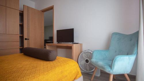 een slaapkamer met een bed, een stoel en een televisie bij Shanarani Apartament in Uruapan del Progreso