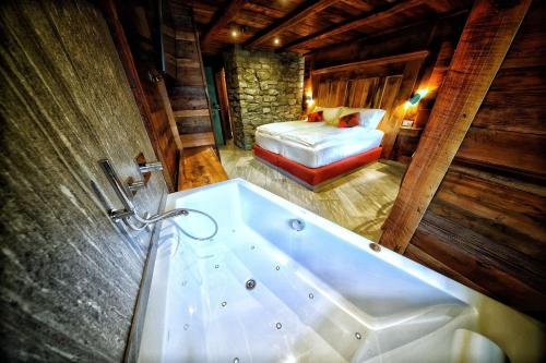a bathroom with a tub and a bed in a room at Café Quinson Relais de Charme in Morgex