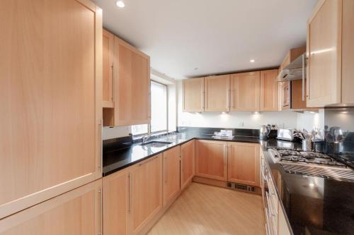 una cocina con armarios de madera y encimeras negras en Roomspace Serviced Apartments - The Courtyard, en Londres