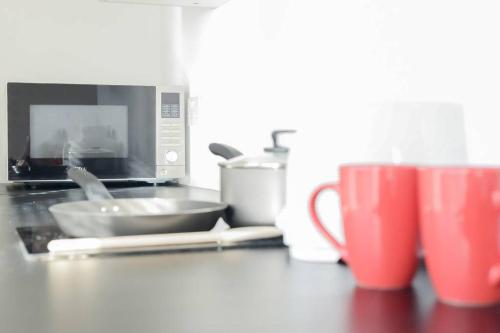 a kitchen counter with a microwave and some cups at City Sparrow Apartment 3 in London