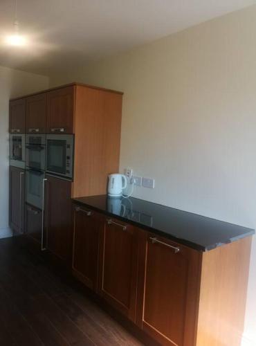 a kitchen with wooden cabinets and a black counter top at Spacious and warm 2 bedroom apartment sleeps up to 5 in Athy