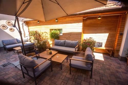a patio with couches and tables and an umbrella at Penzion U Halmů in Hustopeče