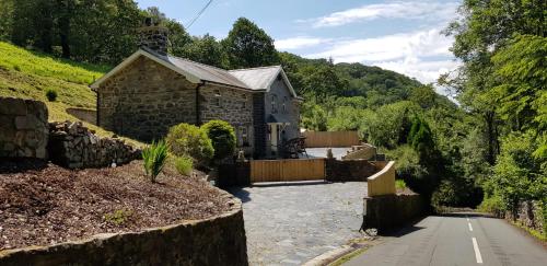 a stone house on a hill with a driveway at Hilltop Cottage/ Penrhiw in Maentwrog
