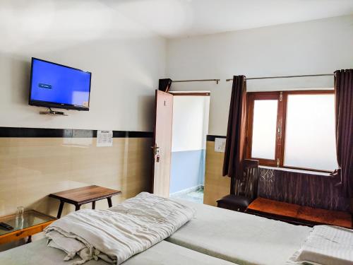 a room with two beds and a tv on the wall at Hotel Goverdhan - Walking to Raja Ki Mandi Railway and 3km from ISBT in Agra