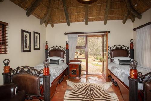 a bedroom with two beds and a sliding glass door at Indalu Game Reserve in Boggomsbaai