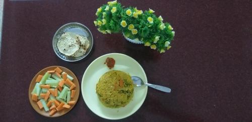 une table avec une assiette de nourriture et un bol de légumes dans l'établissement Hotel Kavijay Sea View, à Dapoli