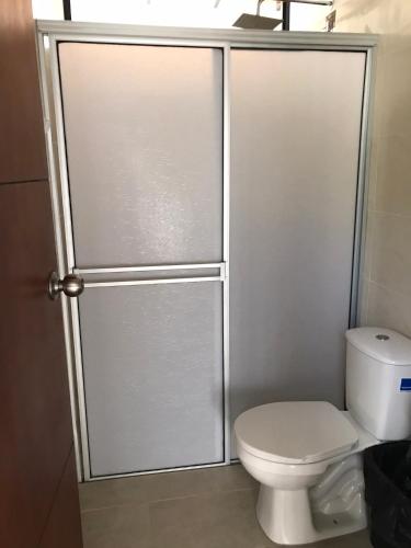 a bathroom with a toilet and a glass shower door at FINCA EL PROGRESO cabañas tipo apartamento in Anapoima