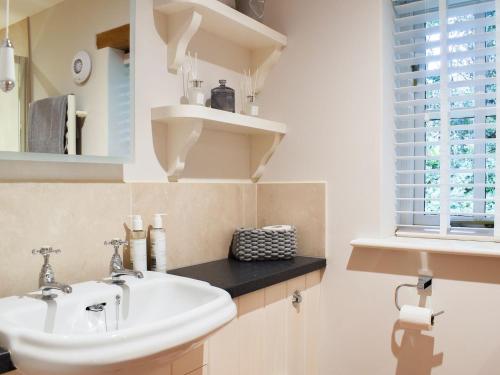 a bathroom with a white sink and a window at The Old Stables 1 in Winterslow
