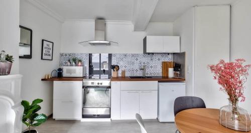 une cuisine avec des armoires blanches et une table en bois dans l'établissement Le Bohème, à Rouen