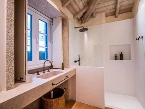 een badkamer met een wastafel, een bad en een raam bij Casa do Gaiteiro 