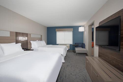 a hotel room with two beds and a flat screen tv at Holiday Inn Express Hotel & Suites Grand Junction by IHG in Grand Junction