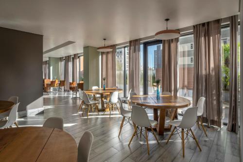 a dining room with tables and chairs and windows at Radisson Blu Belo Horizonte Savassi in Belo Horizonte