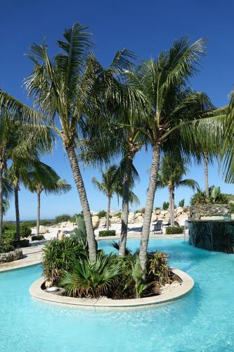 a pool with palm trees in a resort at The Reef 28 Blue Bay Curacao in Sint Michiel