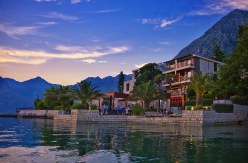 a resort on the water with mountains in the background at Hotel Forza Mare in Kotor