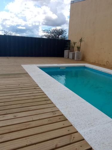 a swimming pool with a wooden deck next to a building at Casa de Juan in Federación