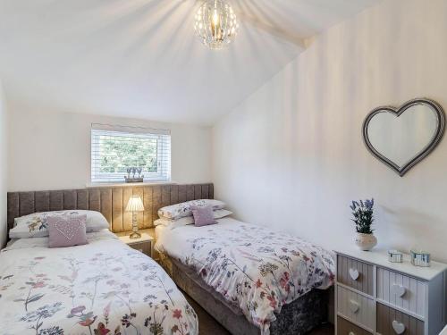 a bedroom with two beds and a heart mirror at Twoo Hoots in Holt