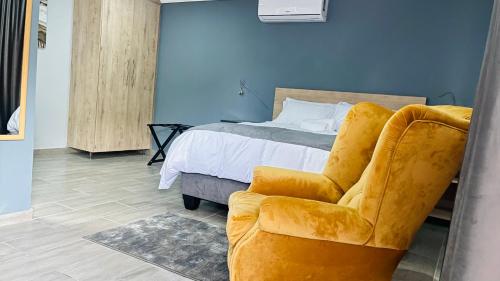 um quarto com uma cama e uma cadeira amarela em Khanyisa Lifestyle em Vereeniging