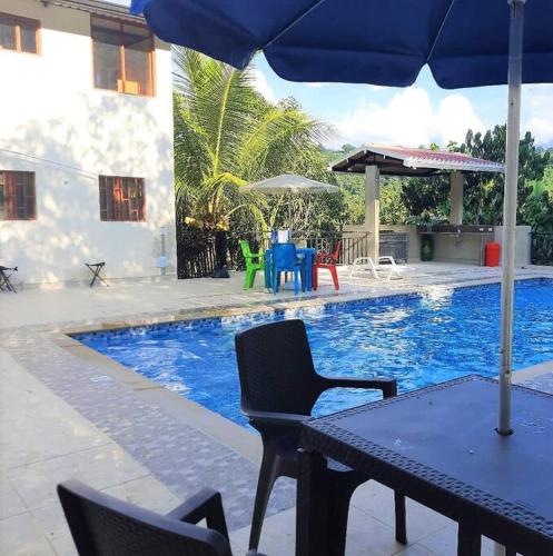 a table with an umbrella next to a swimming pool at FINCA EL PROGRESO cabañas tipo apartamento in Anapoima