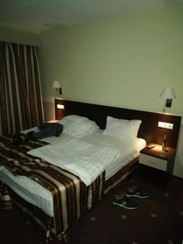 a large bed in a hotel room with shoes on the floor at Hostel Varkaus in Varkaus
