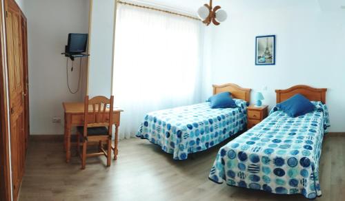 1 dormitorio con 2 camas, escritorio y ventana en Alto Santiago en San Vicente de la Barquera