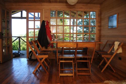 a dining room with a table and chairs and windows at Cabañas Ecoturismo San Miguel in Queilén