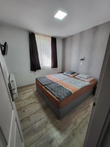 1 dormitorio con 1 cama y suelo de madera en Marika Apartman Sopron en Sopron