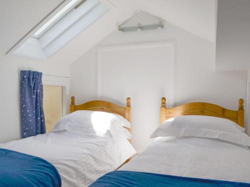 two beds in a bedroom with white walls at Langdale Cottage in Chapel Stile