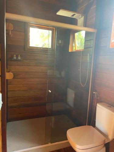 a bathroom with a toilet and a glass shower at Pousada Wind Rose in Itarema