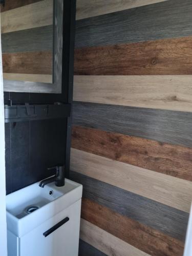 a bathroom with a white sink and wooden wall at Meerblick Wattenmeer ,50m vom Meer,Strand 300m in Westerland