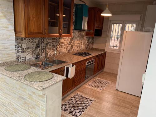 a kitchen with wooden cabinets and a white refrigerator at Le Rocher in Boumerdes