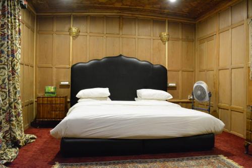 a bedroom with a large bed with a black headboard at New York Houseboat in Srinagar