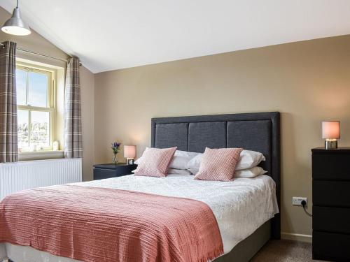 a bedroom with a large bed with pink pillows at Hare Cottage in Westgate