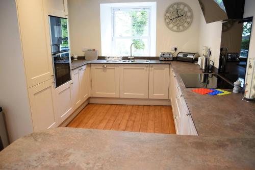 a kitchen with white cabinets and a sink and a window at The Stables in Pitlochry