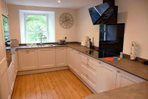 a kitchen with white cabinets and a clock on the wall at The Stables in Pitlochry