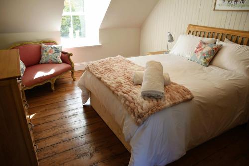 a bedroom with a bed with a blanket and a chair at The Stables in Pitlochry