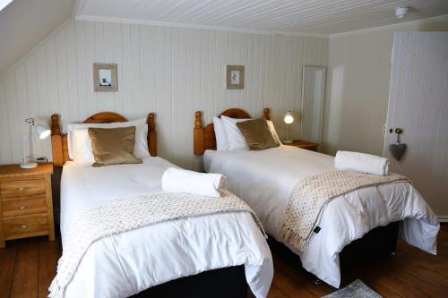 a bedroom with two beds with white comforters at The Stables in Pitlochry