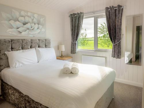 a bedroom with a large white bed with two towels on it at Lodge 6 - Inchyra in Perth