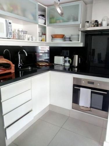 a kitchen with white cabinets and a black counter top at Lux Tower. Departamento 3 ambientes. Pleno centro in Punta del Este