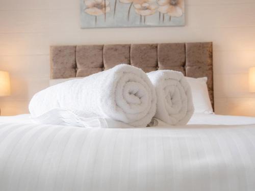 Una cama con toallas blancas encima. en Lodge 8 - The Carse, en Perth