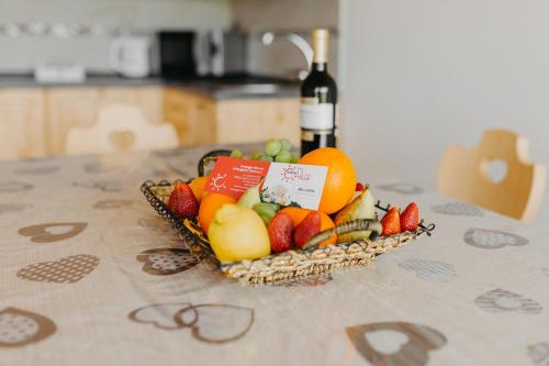 a basket of fruit on a table with a bottle of wine at Alice in Castello Tesino