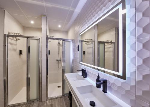 a bathroom with a shower and two sinks and a mirror at ALBERGUE SEGUE O CAMIÑO in Sigüeiro