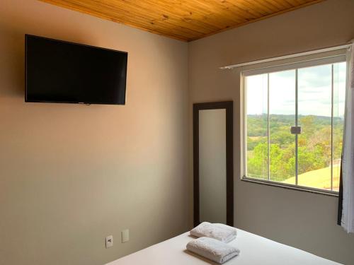 a room with a bed with a television on the wall at Flat dos Bandeirantes in Tiradentes