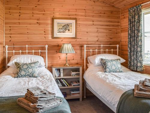 a bedroom with two beds in a log cabin at Islabank Lodge in Auchterarder